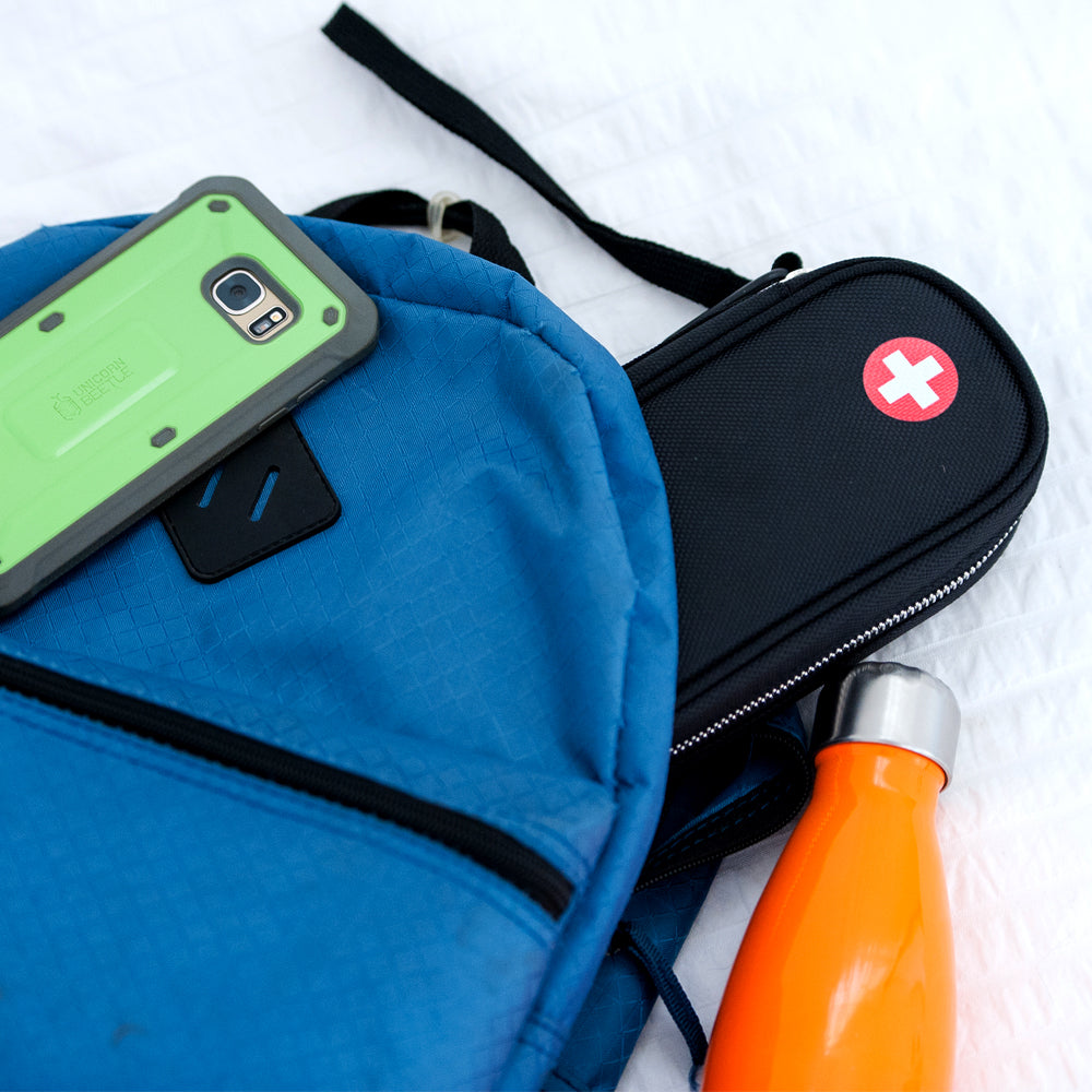 PracMedic Bags black medicine case with red medical cross symbol packed in blue backpack alongside orange water bottle and smartphone for travel convenience