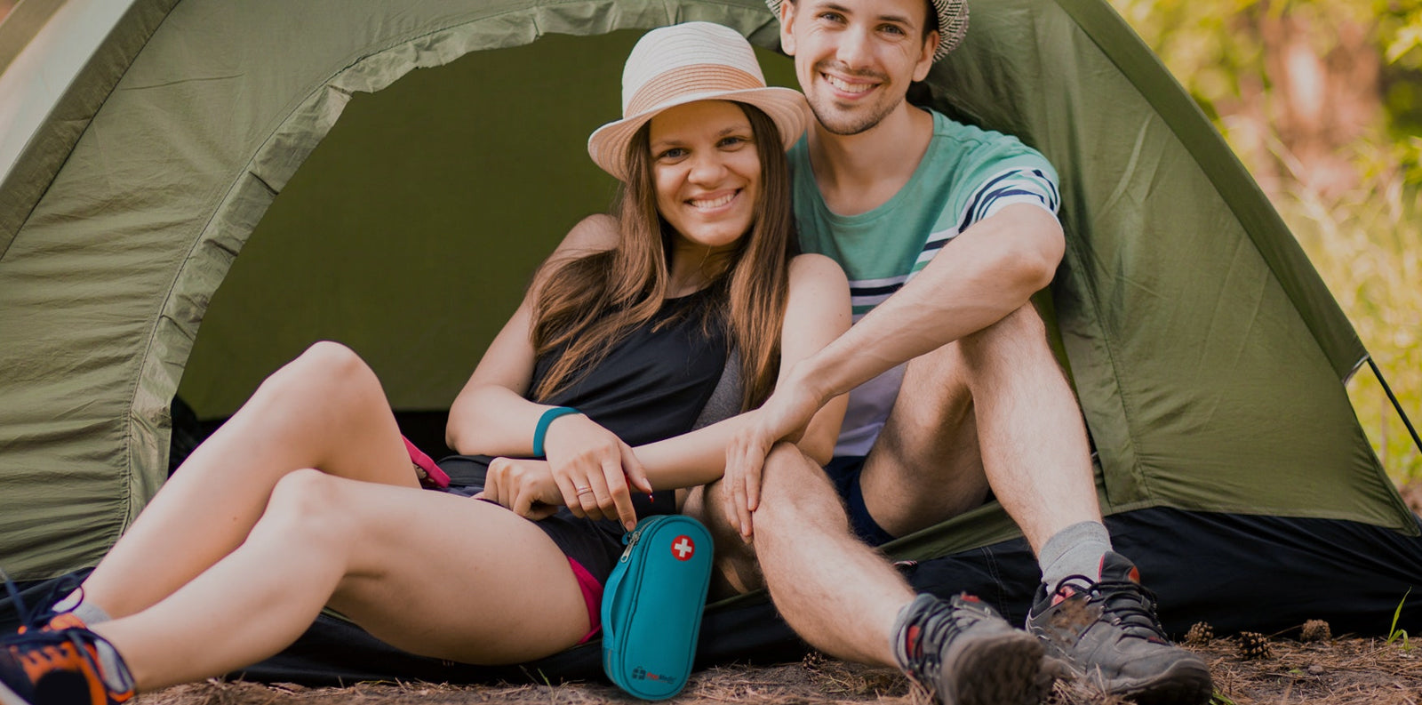 Smiling couple relaxing at a campsite with a PracMedic Bags teal EpiPen carry case, designed for safe storage of emergency allergy medications during outdoor adventures.